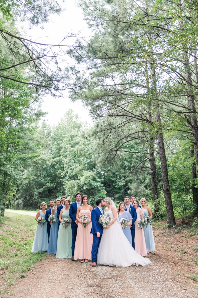 Bride and groom kiss with bridal party Flagstone Farm