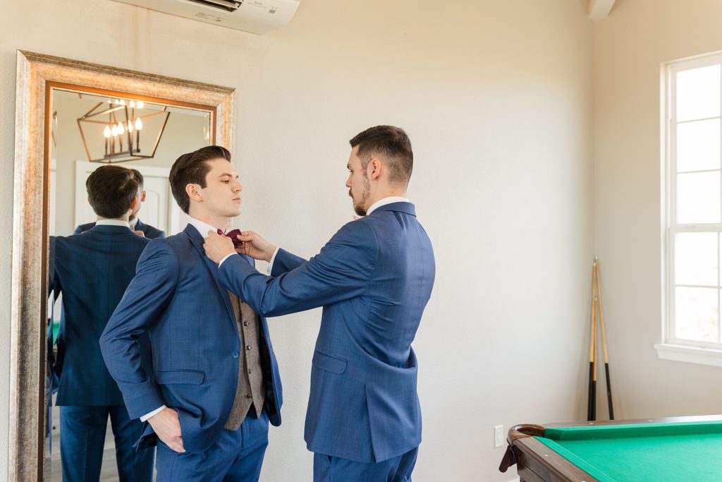 Groomsmen fixes groom's tie in the Grand Ivory groom's suite