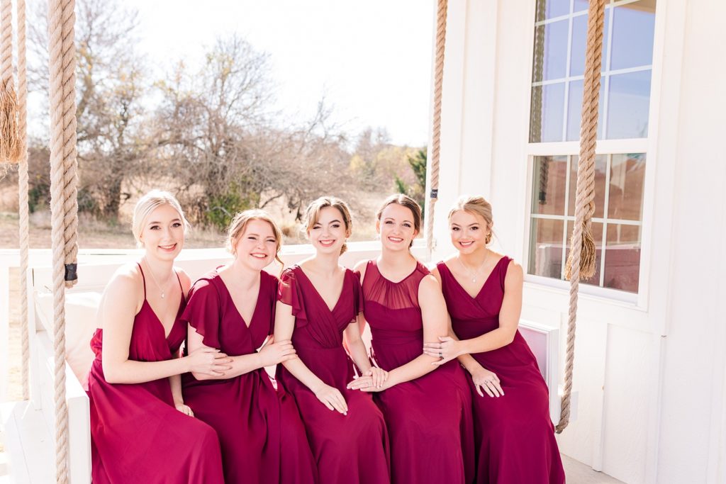 Bridemaids in burgundy dresses on swing in front of brides cottage at the Grand Ivory